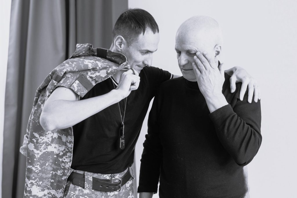 Two veterans in black in white. They are hugging each other and discussing the benefits of a first responder retreat.
