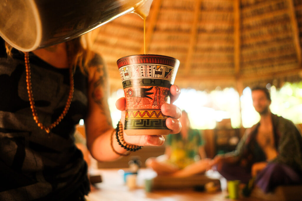 Woman pouring San Pedro plant medicine during a ceremony inside the Costa Rican Maloca during san pedro retreats.