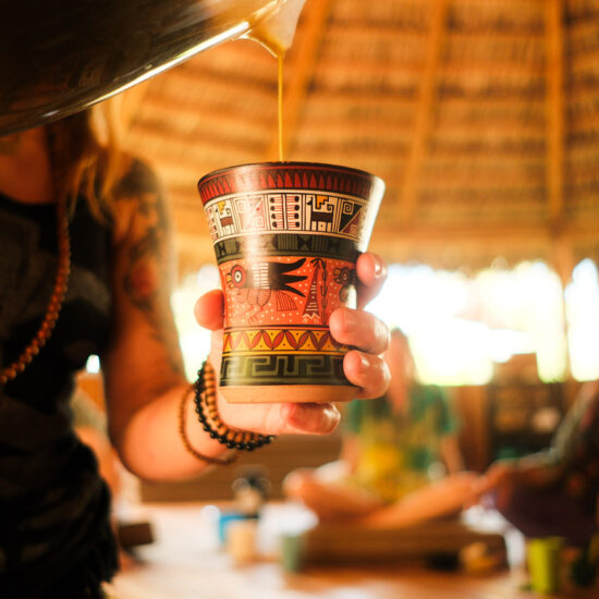 Woman pouring San Pedro plant medicine during a ceremony inside the Costa Rican Maloca during san pedro retreats.