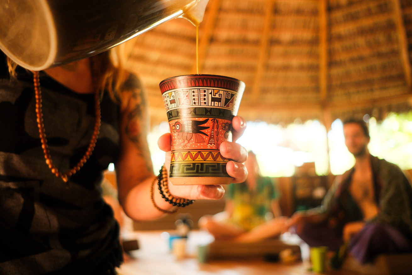 Woman pouring San Pedro plant medicine during a ceremony inside the Costa Rican Maloca during san pedro retreats.